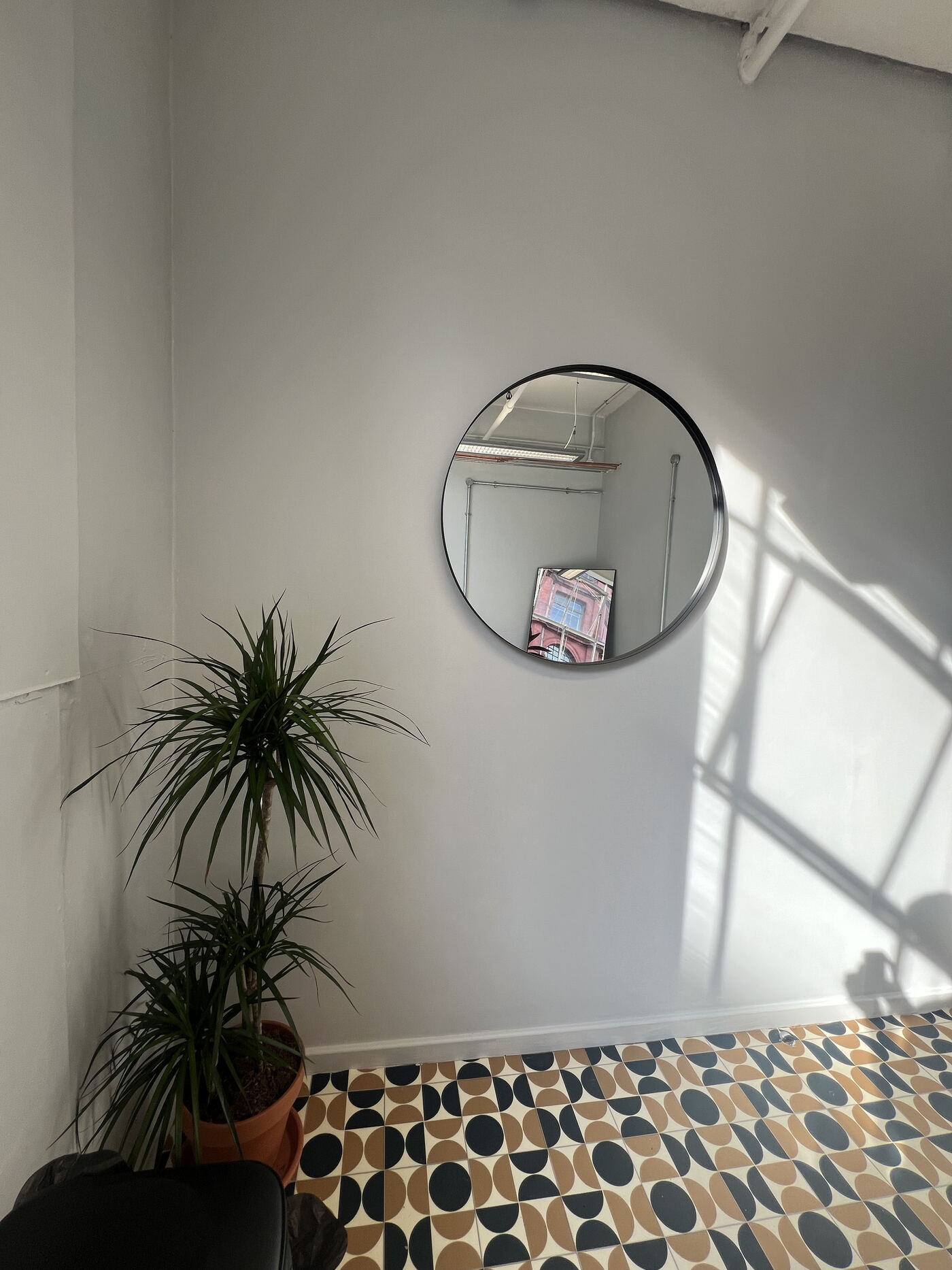 The FORME studio: round mirror, plant and patterned tile floor